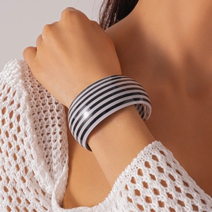 Vista macro di un ampio bracciale in acrilico con strisce bianche e nere al polso