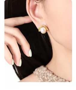 Detailed close-up of a vintage organic gold earring with a round white pearl on a model