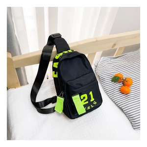 Détail du sac de poitrine en nylon noir pour enfants avec sangles vert néon sur lit blanc