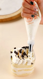Close-up of disposable piping bag decorating an Oreo cupcake with white frosting