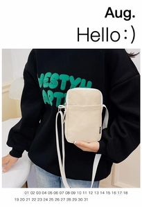 Detail of a cream corduroy crossbody phone bag showing zipper pocket and shoulder strap