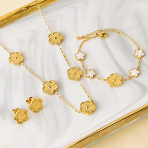 Elegant gold flower jewelry set with white shell inlay on a marble tray display