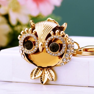 Detailed close-up of golden owl keychain with amber gemstone and sparkling rhinestones