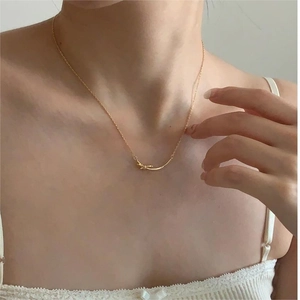 Elegant 925 sterling silver bow necklace in gold finish worn by a model on a white top