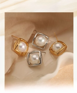 Detail of square gold and silver earrings with round pearls on beige fabric