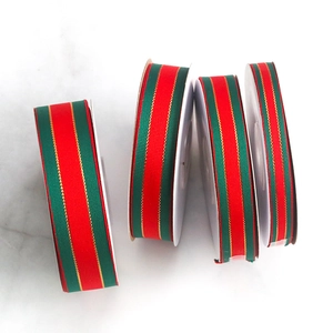 Detail of red and green Christmas grosgrain ribbon with gold metallic edge on marble