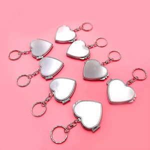 Détail de miroirs de poche pliables en métal argenté en forme de cœur sur fond rose