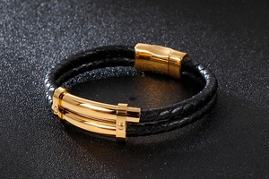 Gros plan sur un bracelet double en cuir tressé noir avec fermoir magnétique doré