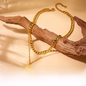 Detail of gold-plated double-layer necklace with evil eye pendant on a rustic branch