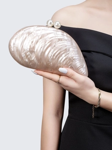 Detail der perlmuttfarbenen Acryl-Clutch in Muschelform mit großem Perlenverschluss und Textur