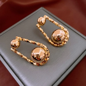 Close-up of golden hammered geometric earrings with shiny sphere on jewelry box