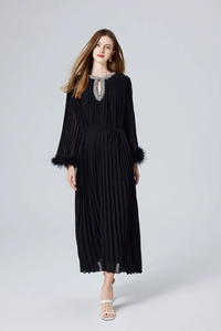 Détail de la robe longue plissée noire avec poignets en plumes et strass au col