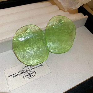 Macro detail of translucent green resin earrings with unique brushed texture on velvet