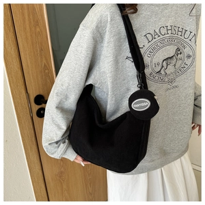 Detail of black corduroy crescent crossbody bag with matching round coin purse on a model