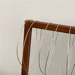Close-up of gold and silver minimalist wave metal headbands on a wooden display