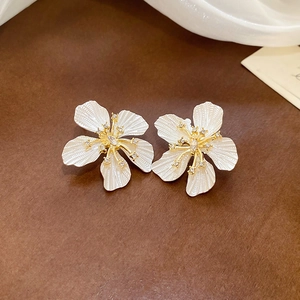 Close-up of white enamel flower earring with gold stamen and sparkling crystal details