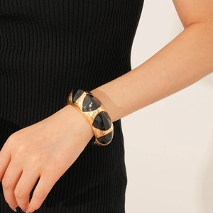 Art Deco style wide open bangle featuring gold metal and black enamel geometric patterns