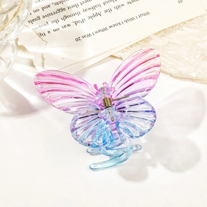 Detail of butterfly hair claw clip with pink and blue gradient resin wings on white desk