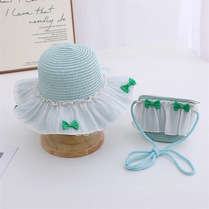 Detail of light blue straw sun hat and matching bag set with lace and green bows
