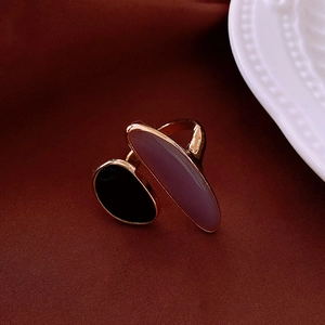 Detail of golden adjustable ring featuring a black stone and translucent purple stone