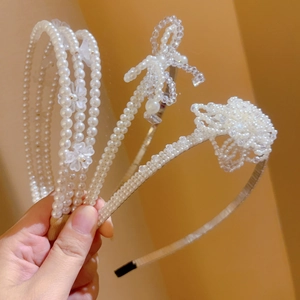 Detailed view of white pearl headbands with floral accents and ribbon bow designs