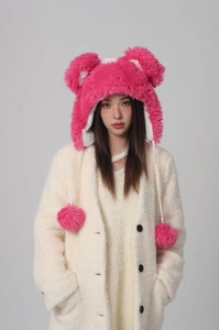 Detail of pink plush bucket hat with bear ears and fluffy pom-pom braided straps