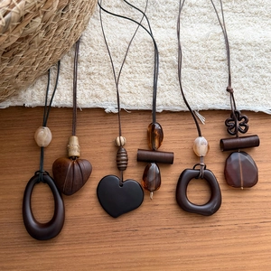 Close-up of geometric wood and resin necklaces in retro Maillard style on wooden desk