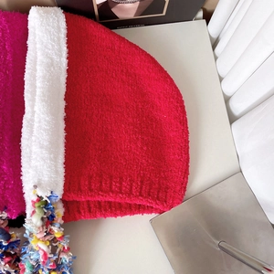 Detail of red and white plush knit hat with colorful pom-poms and fringe tassels