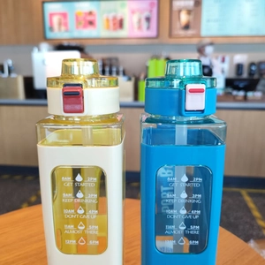 Detail of square plastic water bottles with time markers and integrated straws