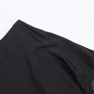 Close-up of black satin fabric with intricate lace trim on asymmetrical blouse