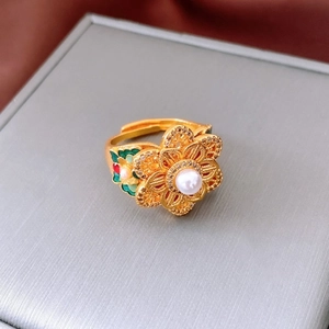 Macro shot of vintage gold flower ring with central pearl and colorful enamel accents