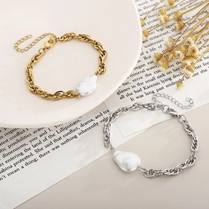 Detailed shot of gold and silver snake bone bracelets with baroque irregular pearls