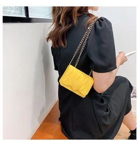 Detail of yellow quilted silicone heart crossbody bag with gold metal chain strap