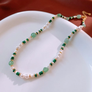 Detail of necklace with green malachite beads, white pearls, and gold lobster clasp