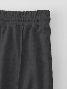 Detail of dark grey waffle knit fabric with breathable texture and elastic waistband
