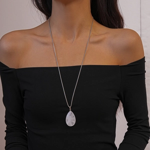 Close-up of a silver-tone necklace featuring a large translucent teardrop stone pendant