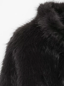 Close-up of the plush black faux fur texture and collar detail on the cropped jacket