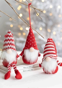 Three plush Christmas gnomes with red knitted hats displayed on books with bokeh lights