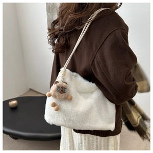 Shoulder view of a large white plush tote bag with a cute brown bear charm for autumn winter
