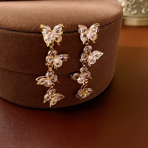 Close-up of long gold butterfly tassel earrings with sparkling cubic zirconia inlay