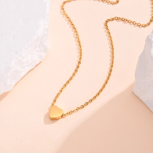 Elegant gold heart pendant necklace for women displayed on natural white stones