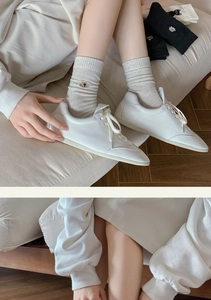 Detailed view of white leather pointed shoes paired with grey embroidered puppy crew socks