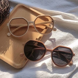 Fashionable beige and pink irregular sunglasses on a wooden tray with a minimalist aesthetic