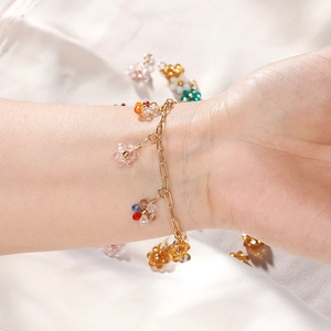 Dettaglio ravvicinato di ciondoli a fiori di cristallo colorati su un bracciale a catena d'oro