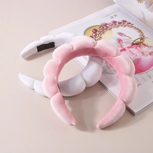 Close-up of pink and white velvet puffy headbands with handmade woven label on a table