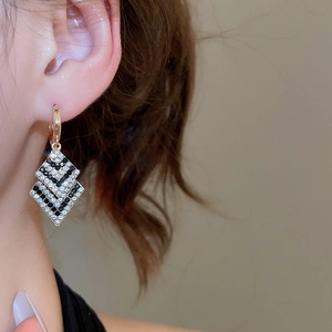 Gros plan de boucles d'oreilles losanges doubles avec cristaux noirs et blancs sur modèle