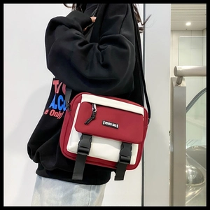 Detail of red and white messenger bag with dual buckle closure and rubber logo