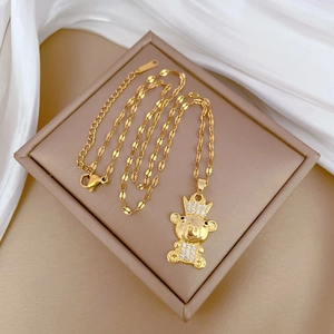 Close-up of golden crown pig pendant with sparkling crystals on a fine link chain necklace