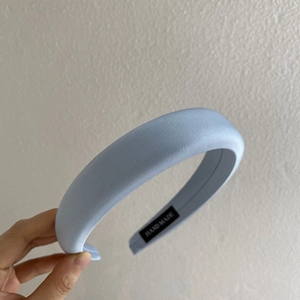 Close-up of handmade blue padded headband showing satin texture and hand made label