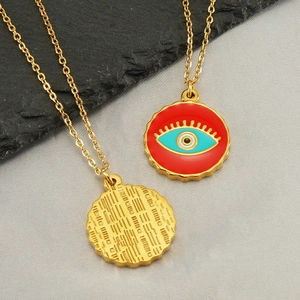 Golden titanium steel Evil Eye necklace with red enamel pendant on stone display